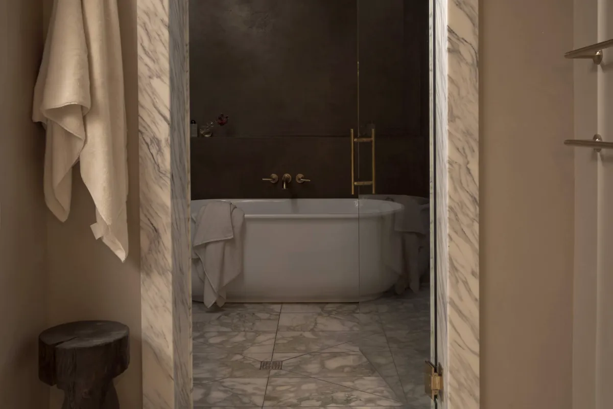Bathroom remodel by Apex Builders: marble-framed doorway opening onto a freestanding tub